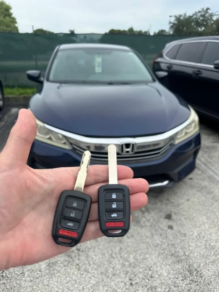 Two new Honda remote head keys in front of a Honda Accord